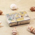 Angled view of the Beach Beauty Zippo Armor lighter with gold-tone details