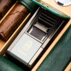 Close-up of a Lubinski cigar accessory in a green leather cigar case with cigars beside it.