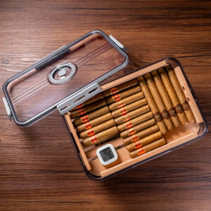 Open glass-trosted humidor lid hinged to the side, showing neatly arranged cigars inside next to a small digital hygrometer on a wooden surface.