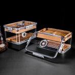 Set of clear acrylic cigar humidors with wooden interiors and cigars, a round hygrometer visible on the lid.