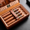 Open brown leather cigar humidor containing five cigars with green bands and a Cigarlounge label visible on the tray edge.