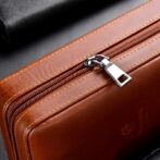 Close-up of a brown leather bag zipper with a silver pull and yellow stitching edge margins.