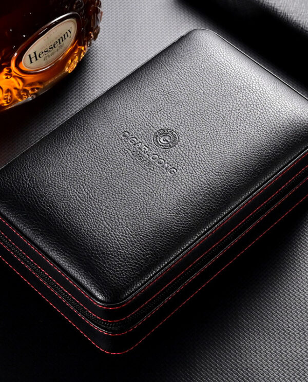 Black leather zippered case or wallet with red contrast stitching and embossed logo on top surface, photographed on a dark textured background.
