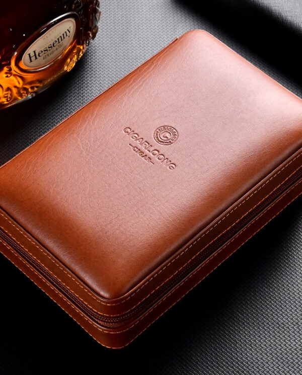Brown leather zippered case with stitching and embossed brand on a dark textured surface; whiskey bottle visible in the background.