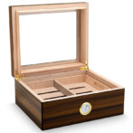 Open wooden cigar humidor with divided inner trays and a brass hygrometer on the front edge.