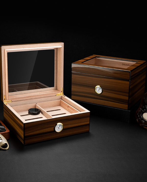 CH003 Open wooden cigar humidor with glass lid showing interior slots and a humidifier, alongside a closed humidor on a dark surface.