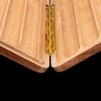 Close-up of a brass hinge joining two light wood panels in a folding joint.