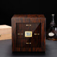Wooden cigar humidor with glass front and gold handles, digital humidity display reading 70% inside a dark room.