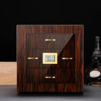 Wooden cigar humidor with glass front and gold handles, showing 70% humidity on a digital hygrometer.