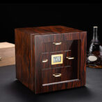 Wooden cabinet-style device with a small digital humidity display showing 70% and gold drawer handles on a dark surface.