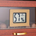 Digital humidity gauge showing 57% inside a wooden cigar humidor.