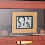 Digital humidity gauge showing 57% inside a wooden cigar humidor.