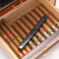 Open wooden humidor with many cigars and a black rectangular humidifier resting across them.
