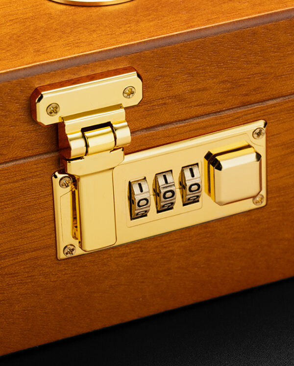 Gold-colored combination padlock on a wooden case or box, with three rotating dials set to 0-0-0 and a brass latch.