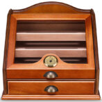 Wooden cigar humidor with a curved top, three interior shelves, a brass hygrometer in the front center, and two lower drawers.