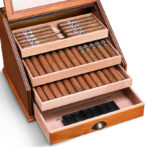 Open wooden cigar humidor with multiple drawers filled with neatly arranged cigars inside the compartments, ready for storage and aging.