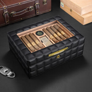 Black quilted leather cigar humidor with a glass lid, showing cigars neatly arranged inside and a small hygrometer visible on the top panel.
