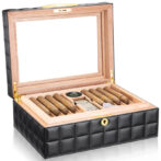 Open wooden humidor with black quilted exterior, cigars neatly arranged and a humidity gauge visible inside the lid.
