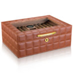 Brown leather square cigar humidor with a glass lid showing cigars inside and a gold latch label.