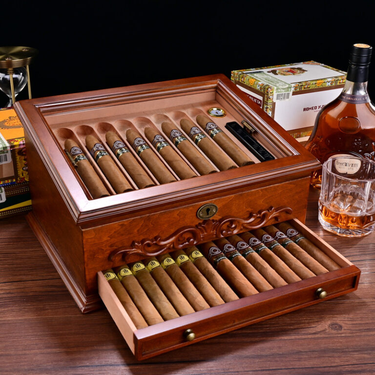 Open wooden cigar humidor with cigars arranged in rows; drawer pulled out showing more cigars.