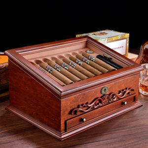 Polished wooden cigar humidor opened to reveal a row of cigars resting in a built-in tray with a key lock and decorative carving on the front panel.