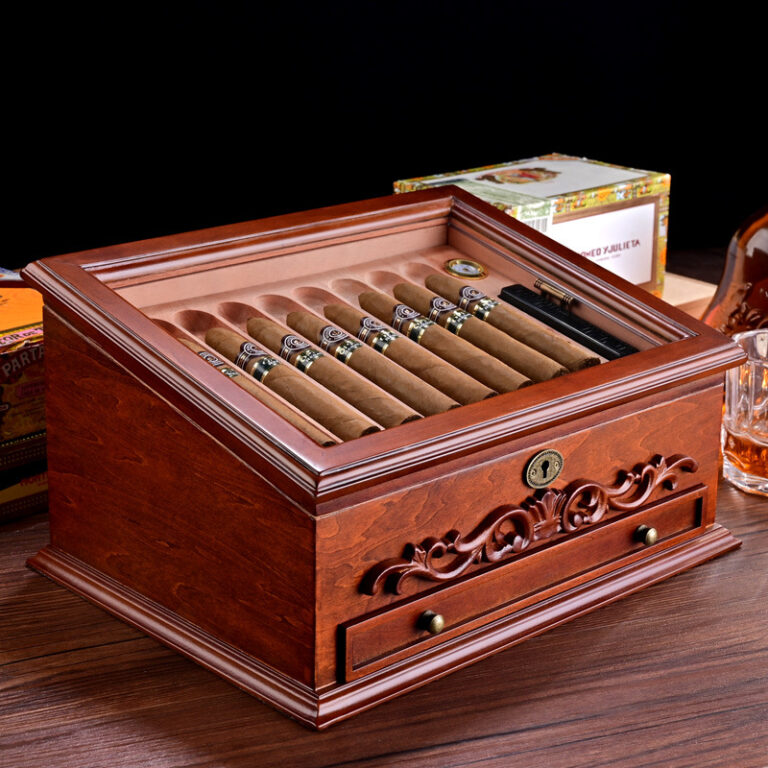 Polished wooden cigar humidor opened to reveal a row of cigars resting in a built-in tray with a key lock and decorative carving on the front panel.
