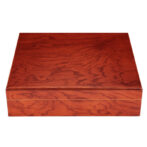 Rectangular wooden box with a polished reddish-brown finish and visible grain patterns, closed against a white background.