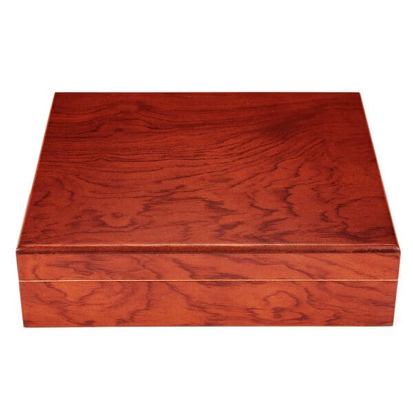 Rectangular wooden box with a polished reddish-brown finish and visible grain patterns, closed against a white background.