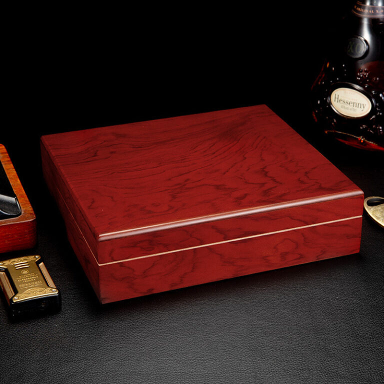 Polished red-brown wooden box on a black surface, with a bottle of Hennessy cognac in the background.
