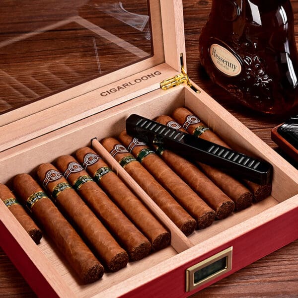 CH019-02 Cigar humidor open with multiple cigars lined up, a cutter resting on top, and a bottle of cognac nearby.