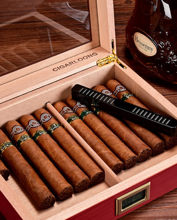 CH019-02 Cigar humidor open with multiple cigars lined up, a cutter resting on top, and a bottle of cognac nearby.