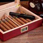 Open wooden cigar humidor with seven cigars inside and a digital humidity/temperature display on the front.