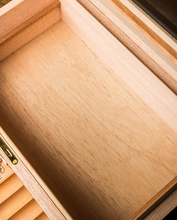 CH020-03 Interior of a light wood cigar humidor drawer with brass hardware and a small round hygrometer in the corner, empty inside.