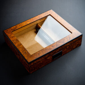 Wooden display box with a glass lid on a dark textured surface, empty interior and small latch on the side