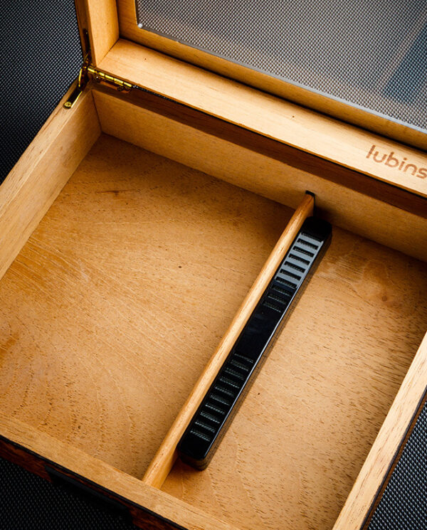 CH021-03 Open wooden box with a black handheld measuring tool resting diagonally inside; inner edge is stamped with 'lubinski'