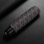 Slim device wrapped in a brown patterned fabric sleeve on a dark surface, showing a chevron-like design and black ends.