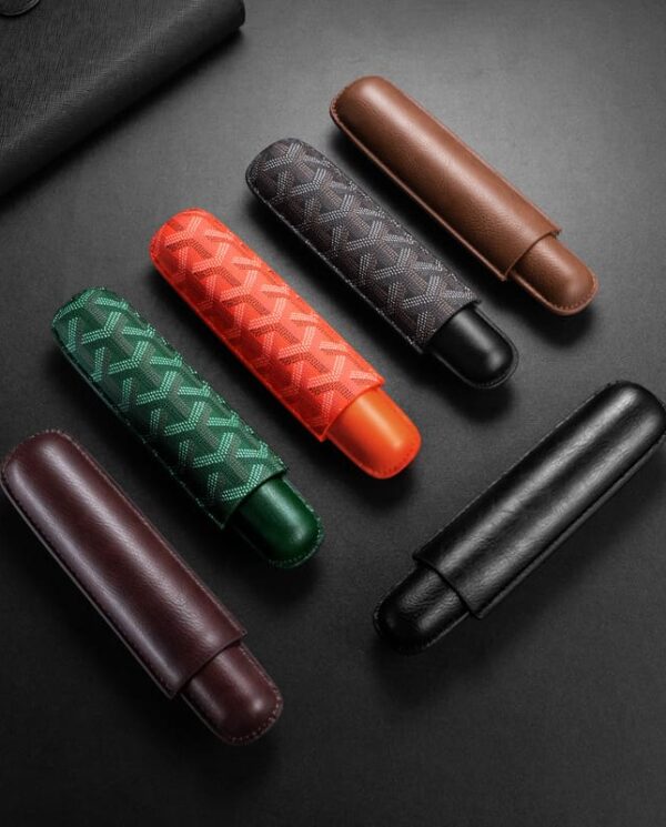 CL030 Six leather eyeglass cases in black, brown, burgundy, green, red, and gray with patterned fabric exteriors on a dark surface.