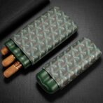 Green patterned leather cigar case with two cigars partially exposed at the open end, on a dark textured surface.