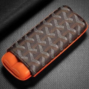 Brown patterned fabric case with orange interior, likely a glasses or accessory case on a textured surface.