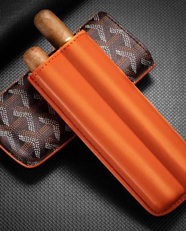 CL033-02 Orange leather double cigar sleeve with two cigars protruding, resting on a brown monogrammed case.