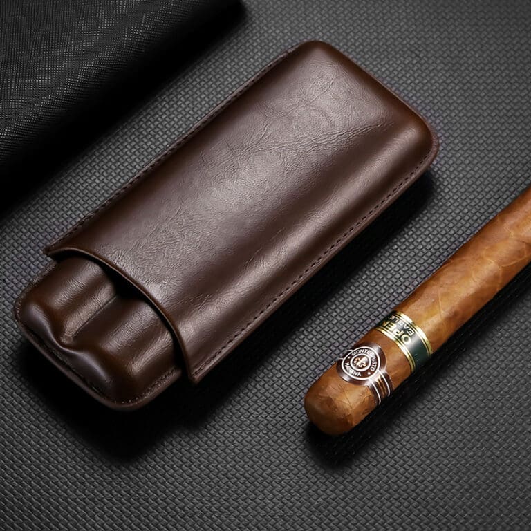 CL034-01 Brown leather cigar case beside a partially smoked cigar on a dark textured surface; a premium smoking accessory set up for display.