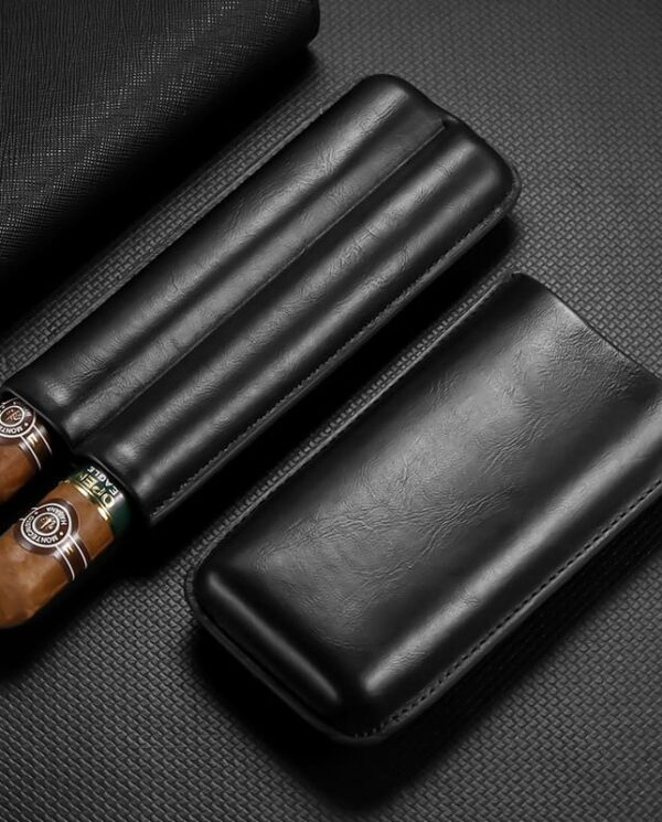 Black leather cigar case with two cigars partially removed, resting on a dark textured surface