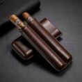 Two cigars with light bands resting in a dark brown leather cigar case on a textured black surface.