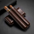 Two cigars with light bands resting in a dark brown leather cigar case on a textured black surface.