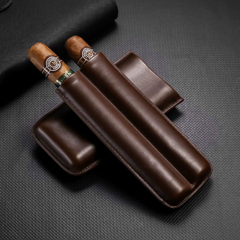 Two cigars with light bands resting in a dark brown leather cigar case on a textured black surface.
