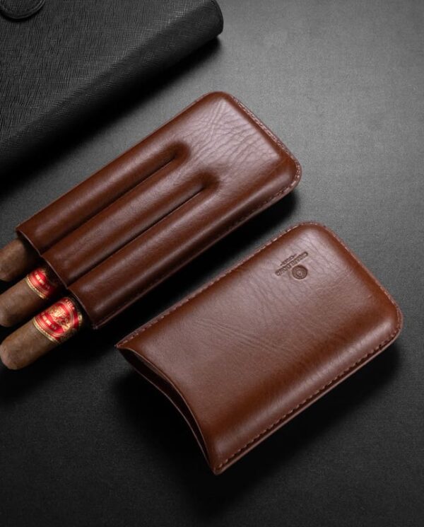 CL035 Brown leather cigar case open with three cigars beside a black leather wallet on a dark surface.