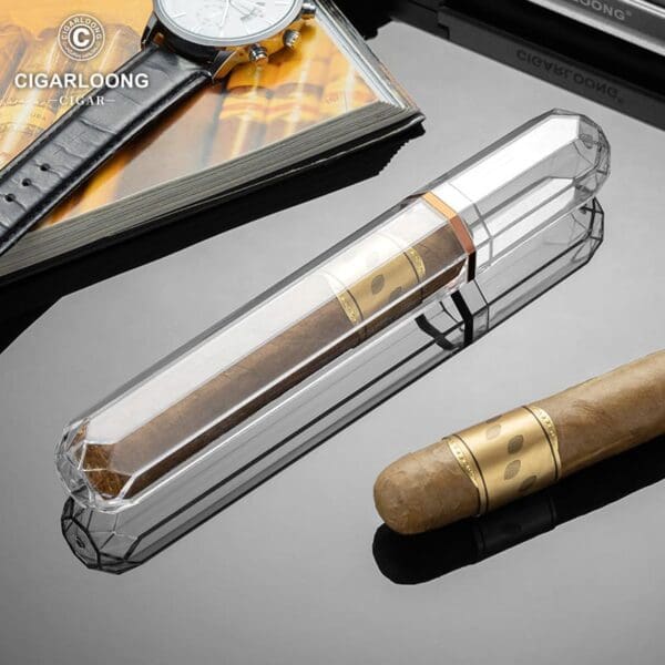 Crystal cigar tube on a reflective surface with a brown cigar nearby and a magazine and watch in the background.