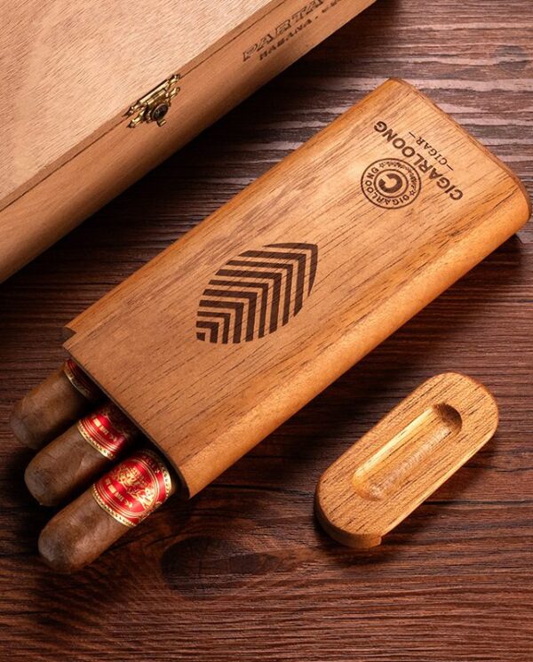 CL041-02 Wooden cigar box with three cigars sticking out on a dark wooden table, lid nearby with carved logo.