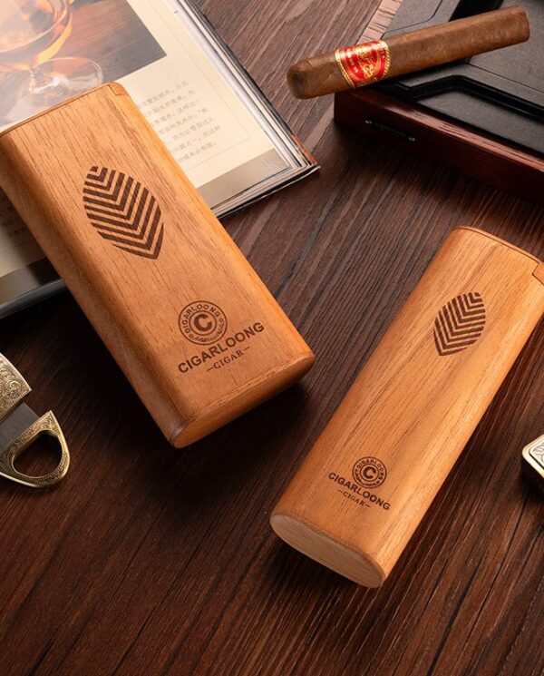 CL041 Two wooden cigar cases with leaf logo and brand name on a dark wooden table, accompanied by a cigar, lighter, and an open book/album nearby.