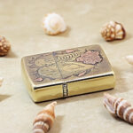 Angled detail of the Beauty and Skulls Zippo Armor lighter and its engraved brass finish